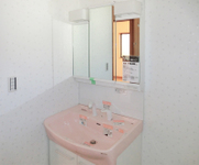 【洗面室】淡いピンクがかわいらしい洗面台です。
3面鏡の後ろには、散らかりがちな小物やボトルなどがスッキリ収まります。
壁紙もかわいいものを選択しました。